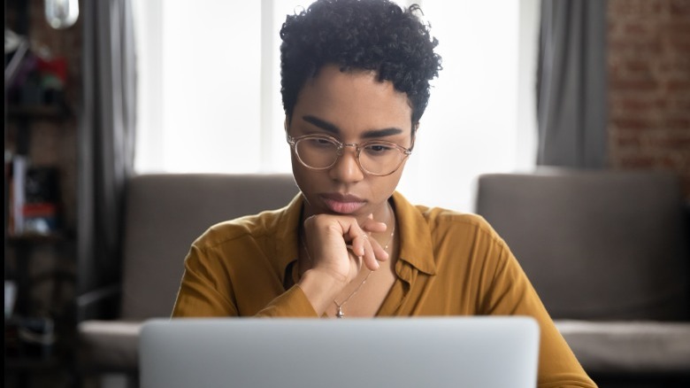Woman looks at her laptop pensively