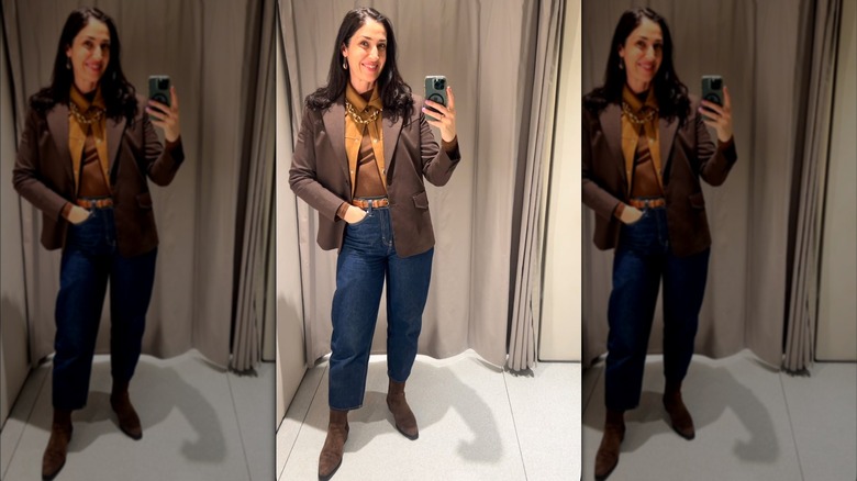 A woman taking a mirror selfie wearing a layered outfit