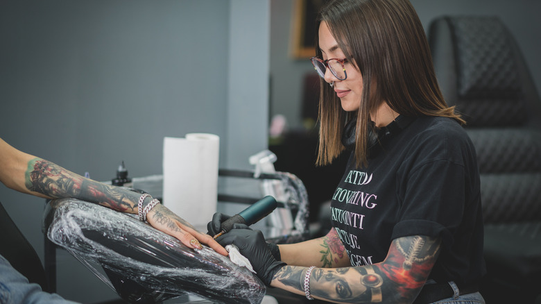 woman tattooing hand 