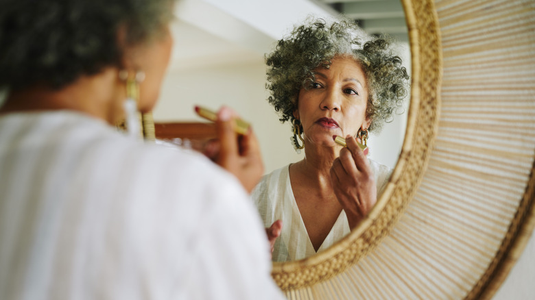 older woman applying lipstick