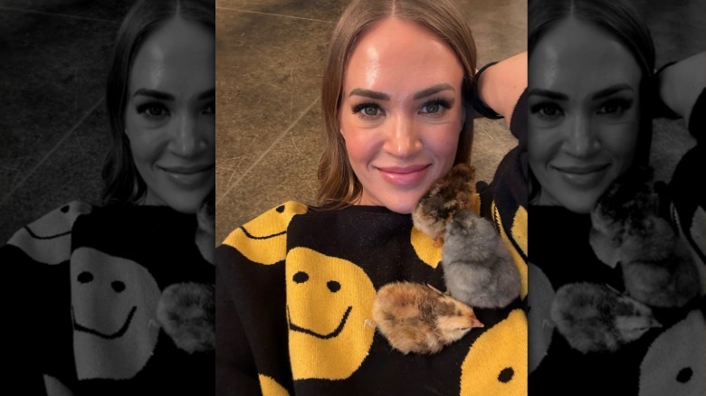 Carrie Underwood smiles as three chicks settle on her chest