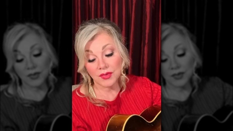 Stella Parton strumming her guitar and singing